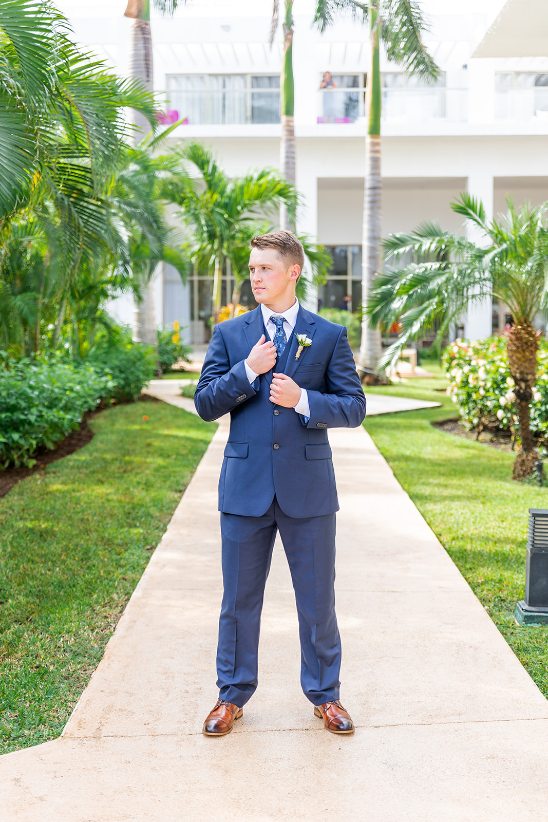 A groom wearing a navy blue suit and tie before his beach destination wedding at the Princess Yucatan resort.